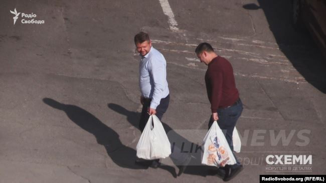 Двоє чоловіків несуть пакети з продуктами до управління СБУ