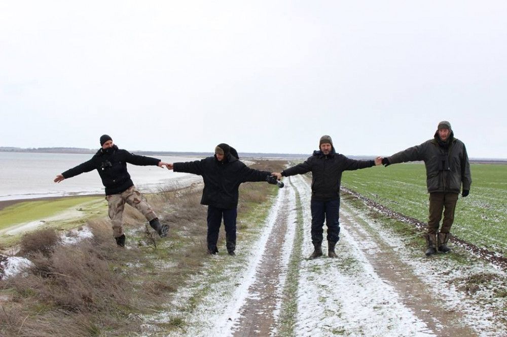 Сотрудники НПП «Тузловские лиманы", взявшись за руки, показывают остатки прибрежной полосы в нацпарке